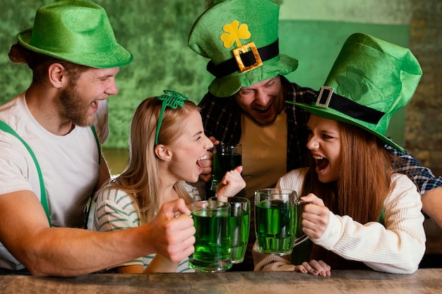 Kostenloses Foto glückliche freunde feiern zusammen st. patrick's day mit getränken an der bar