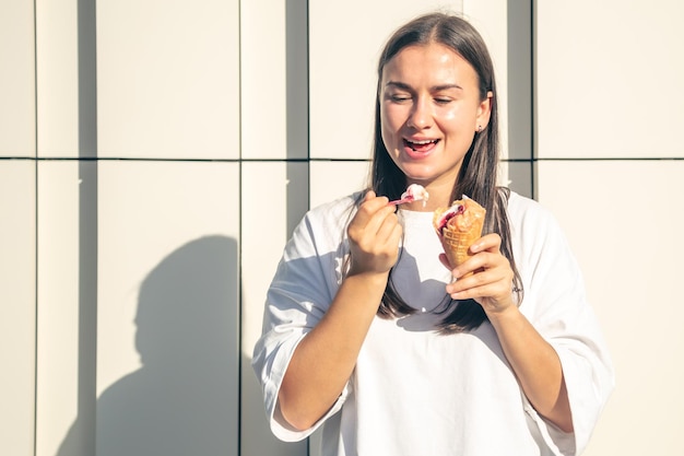 Glückliche junge Frau mit köstlichem Eis in Waffelkegel im Freien