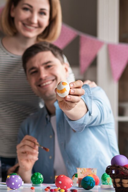 Glückliche Mutter und Vater, die gemalte Eier für Ostern zeigen