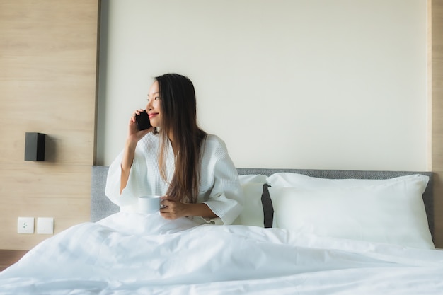 Kostenloses Foto glückliches lächeln der schönen jungen asiatischen frauen des porträts mit kaffee und handy