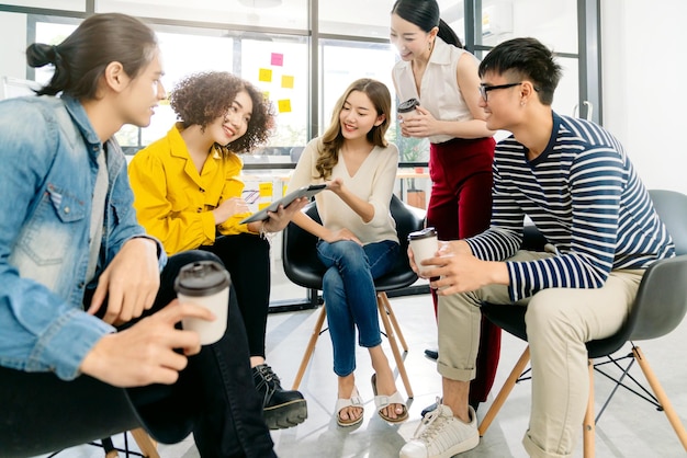 Kostenloses Foto gruppe asiatischer junger kreativer glücklicher unternehmer auf einem geschäftstreffen im bürohintergrund gute führung und teamarbeit führen zum erfolg