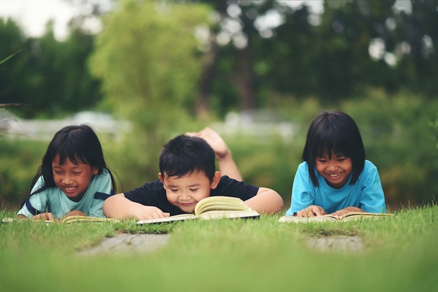 Kostenloses Foto gruppe kinder, die das lesen auf rasenfläche liegen