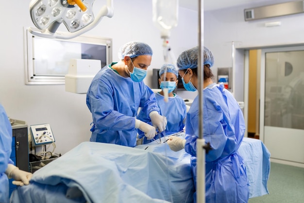 Kostenloses Foto gruppe von ärzteteams, die dringend chirurgische eingriffe durchführen und patienten im theater im krankenhaus helfen medizinisches team, das chirurgische eingriffe in einem hellen, modernen operationssaal durchführt