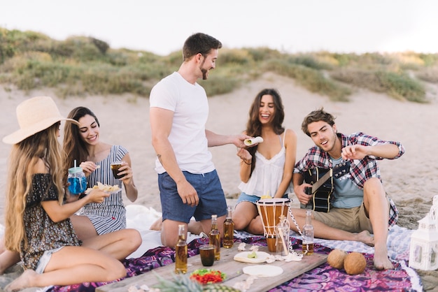 Kostenloses Foto gruppe von freunden sitzen auf dem sand