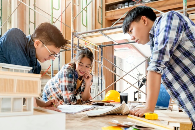 Kostenloses Foto gruppe von innenarchitekturteams intelligenter asiatischer architekten, die sich mit bauingenieuren beraten, brainstrom-treffen mit hausprojektplan und hausmodell im hintergrund der hausrenovierungsstruktur