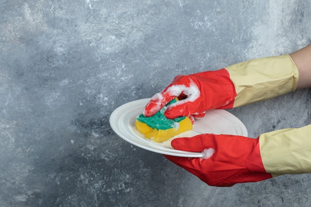 Kostenlose Foto hände in schutzhandschuhen waschplatte mit schwamm.