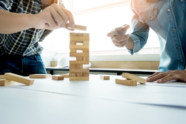 Kostenloses Foto hand des ingenieurs spielen eine blöcke holz turm spiel (jenga) auf blaupause oder architektonisches projekt