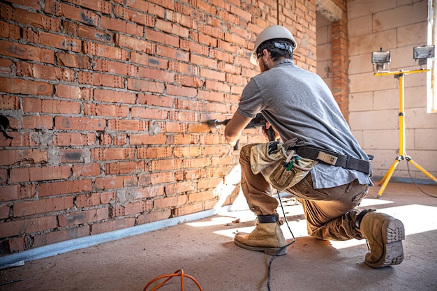 Heimwerker auf einer Baustelle beim Bohren einer Wand mit einem Perforator