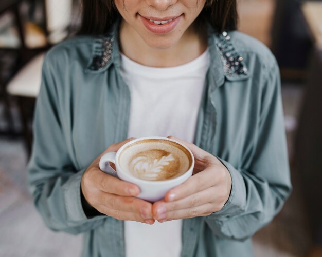 Hübsche junge Frau, die eine Kaffeetasse genießt