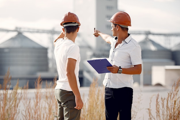 Ingenieure in Helmen, die zur Fabrik stehen