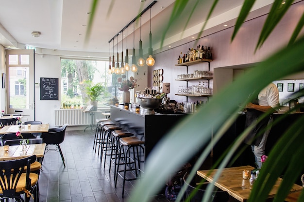 Kostenloses Foto innenaufnahme eines cafés mit stühlen nahe der bar mit holztischen