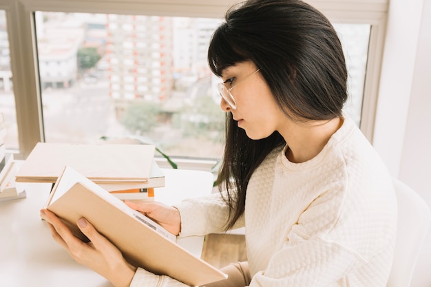 Intelligente Frau, die am Tisch liest