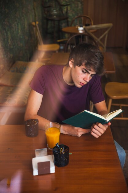 Jugendlich Jungenleseboy im netten Café