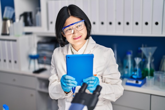 Kostenloses Foto junge chinesische wissenschaftlerin mit touchpad im labor arbeiten