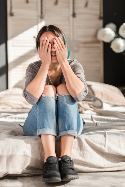 Kostenlose Foto junge frau, die auf dem bett schließt ihre augen sitzt