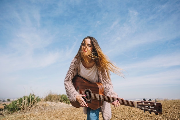 Junge Frau, die Gitarre in der Natur spielt