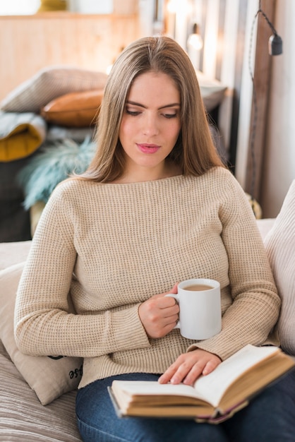 Kostenloses Foto junge frau, die weißes tasse kaffee-lesebuch hält