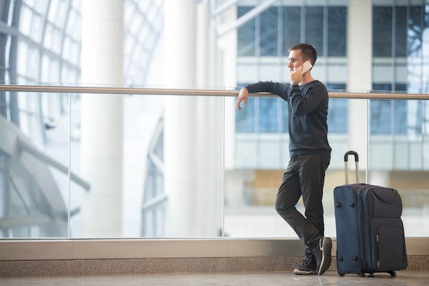 Kostenloses Foto junge reisende reden über smartphone im flughafen