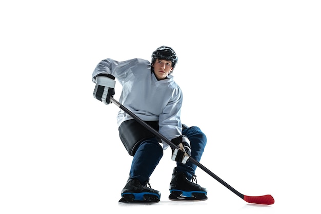 Kostenloses Foto junger männlicher hockeyspieler mit dem stock auf eisplatz und weißer wand