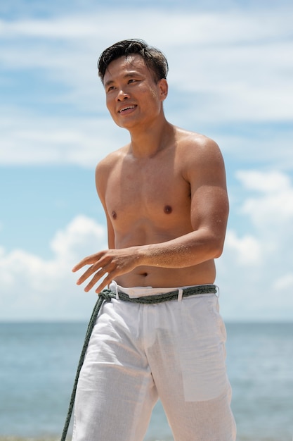 Kostenloses Foto junger mann am strand bereitet sich darauf vor, capoeira zu üben