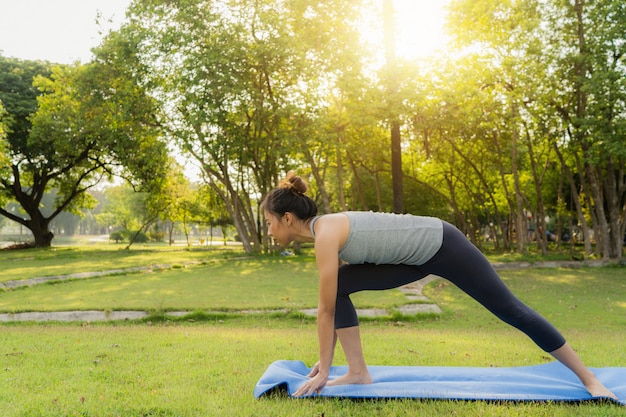 Junges asiatisches Frauenyoga draußen halten ruhig und meditieren beim Üben von Yoga