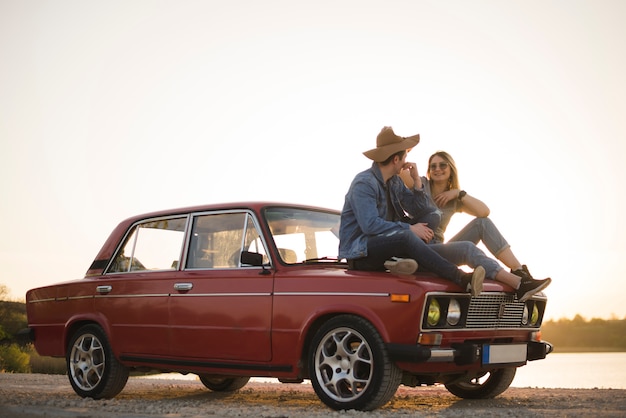 Kostenloses Foto junges paar sitzt auf einem oldtimer