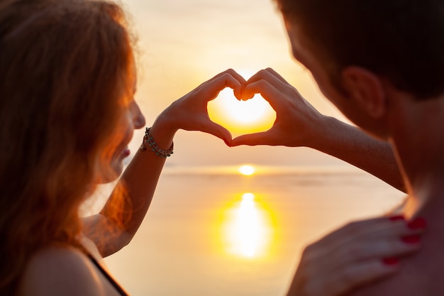 Kostenloses Foto junges sexy romantisches paar in der liebe glücklich am sommerstrand zusammen, der spaß hat, badeanzüge zu tragen, die herzzeichen auf sundet zeigen