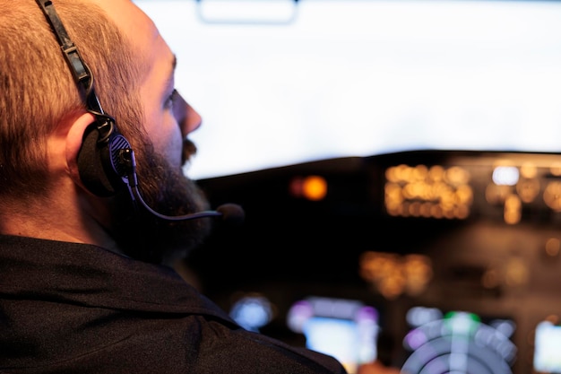 Kostenloses Foto kaukasischer kapitän, der den flugzeug-cockpit-befehl verwendet, um jet zu fliegen, armaturenbrett- und bedienfeldtasten drückt. navigations-windschutzscheibe mit radarkompass für den internationalen flugdienst. nahansicht.