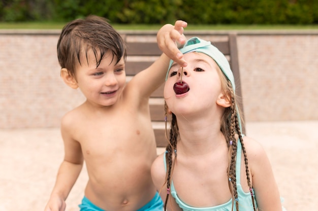 Kinder essen Kirschen am Pool