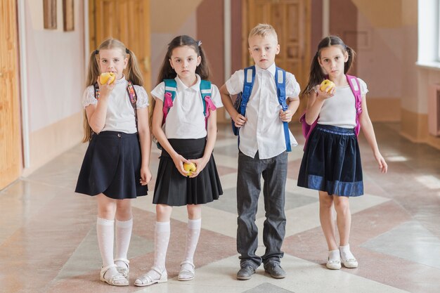 Kinder mit den Äpfeln, die im Schulkorridor stehen