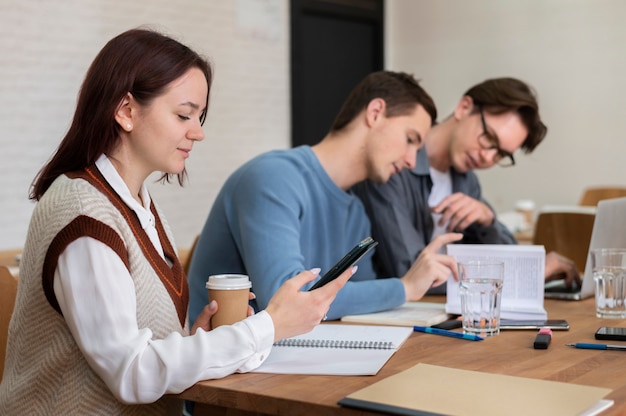 Klassenkameraden benutzen Smartphone während des Gruppenstudiums