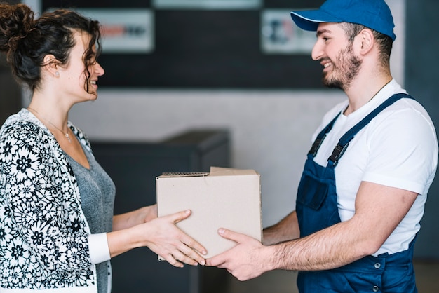 Lächelnde Frau und Kurier mit Paket