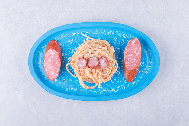 Kostenloses Foto leckere spaghetti mit würstchen auf blauem teller.