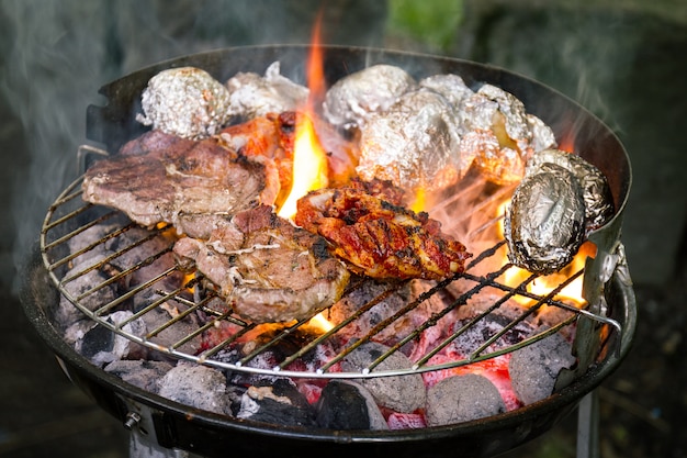 Kostenloses Foto leckeres frisches appetitliches fleisch rindfleisch auf grill kochen auf offenem feuer auf grill raster. natur hintergrund. nahansicht.