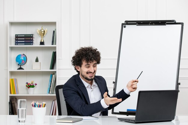 Lehrer Brünette Ausbilder mit Computer im Anzug und Whiteboard im Klassenzimmer lächelnd