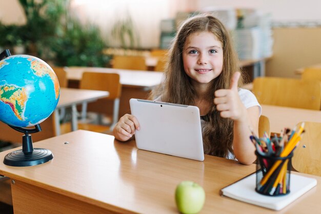 Mädchen gestikulieren Daumen mit Tablette