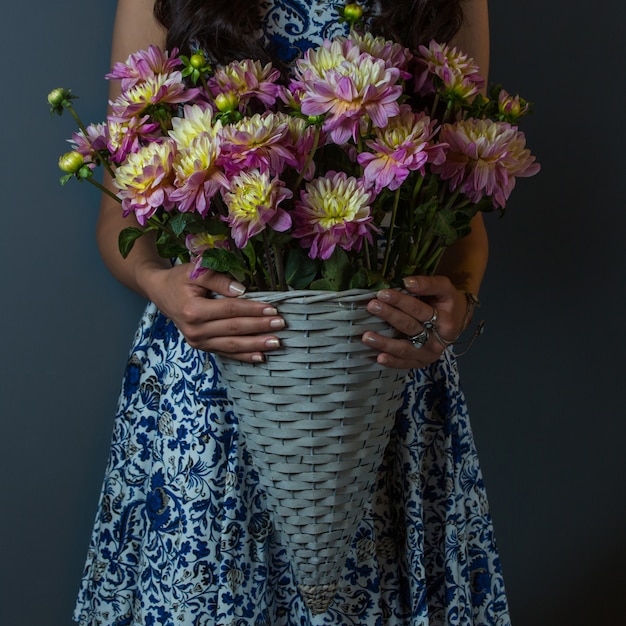 Kostenloses Foto mädchen im musterkleid, das einen blumenstrauß von gartennelken hält