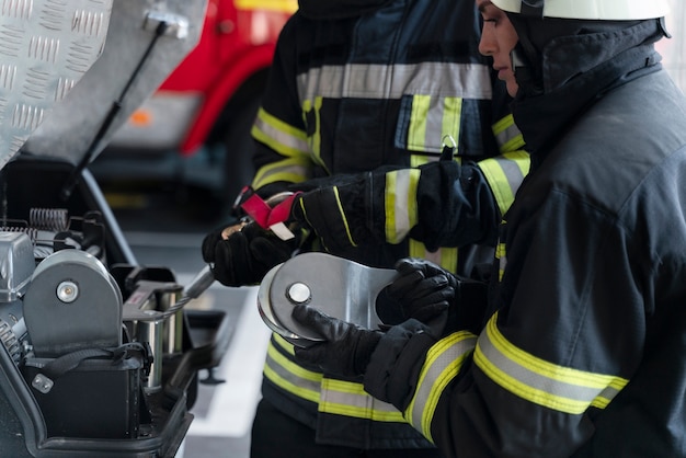 Kostenloses Foto männliche und weibliche feuerwehrleute arbeiten in anzügen und helmen zusammen