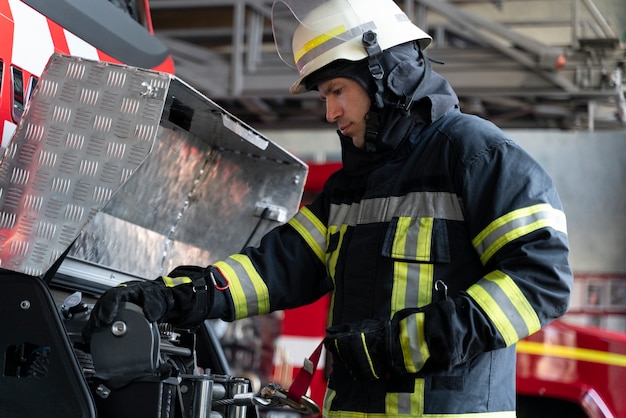 Kostenloses Foto männlicher feuerwehrmann am bahnhof mit anzug und schutzhelm