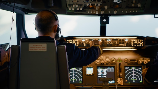 Kostenloses Foto männlicher flugkapitän, der höhen- und längentasten fixiert, mit dem dashboard-navigationsbefehl und dem bedienfeld. fliegendes flugzeug mit flugzeugbesatzung und radarkompass, triebwerk und windschutzscheibe.