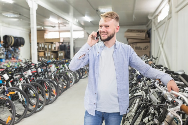 Mann, der auf Mobiltelefon in der Fahrradwerkstatt spricht