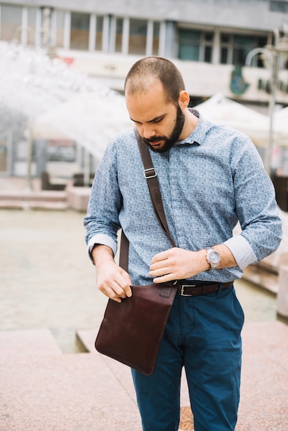 Kostenloses Foto mann, der nach etwas in der tasche sucht