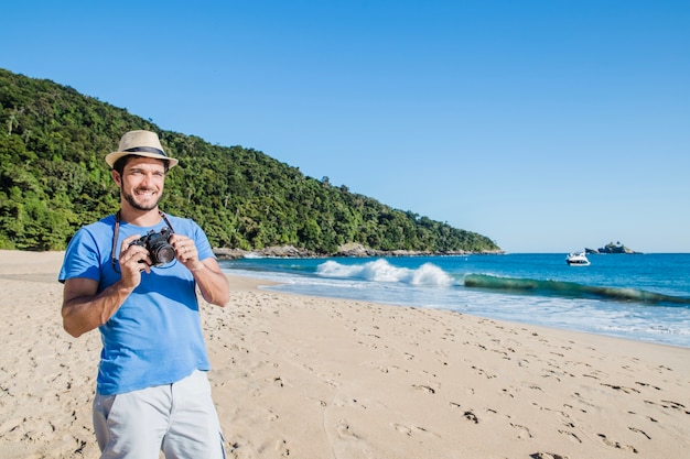 Kostenloses Foto mann hält kamera am strand