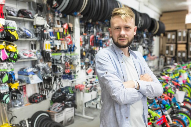 Mechaniker mit den gefalteten Armen, die in der Fahrradwerkstatt stehen