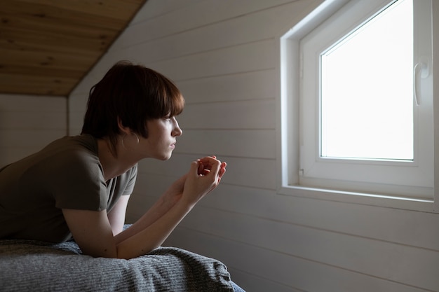 Kostenlose Foto mittlere schussfrau, die heraus das fenster schaut