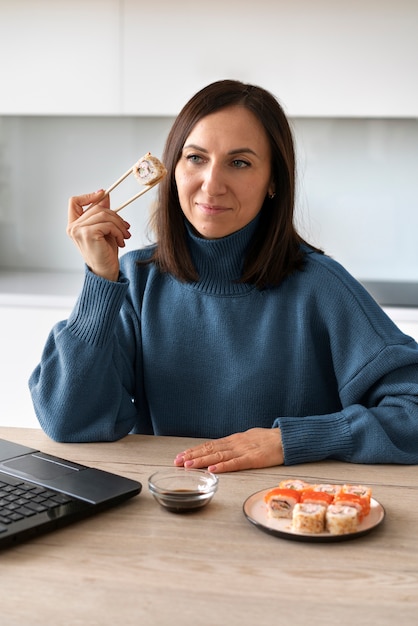 Mittlere Schussfrau, die zu Hause Sushi isst