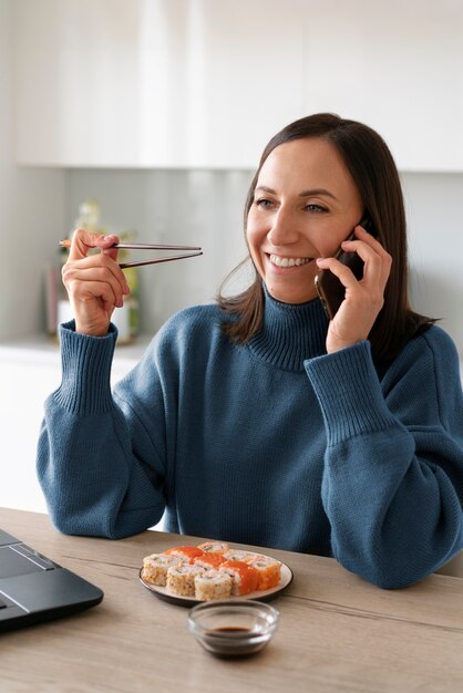 Mittlere Schussfrau, die zu Hause Sushi isst