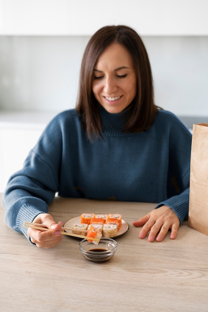 Mittlere Schussfrau, die zu Hause Sushi isst