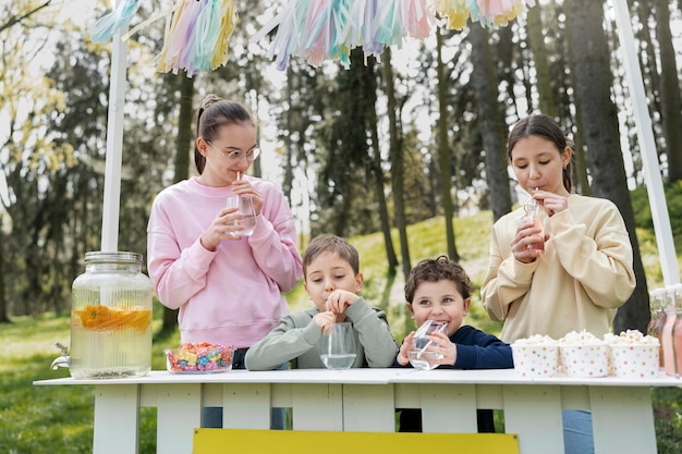 Kostenloses Foto mittlere schusskinder, die draußen limonade trinken