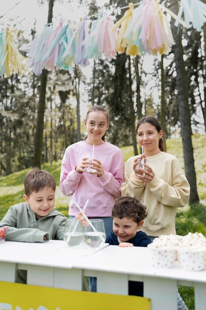 Kostenloses Foto mittlere schusskinder, die draußen limonade trinken